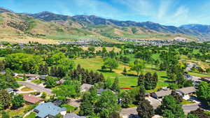 Aerial view of property and surrounding area with a mountain backdrop and nearby suburban area