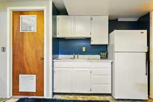 Kitchen featuring freestanding refrigerator, white cabinetry, and light countertops