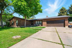 Ranch-style house with brick siding, concrete driveway, a garage, and a front lawn