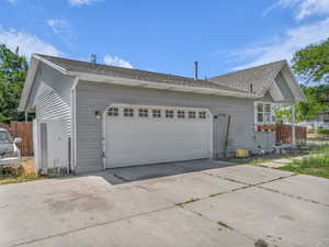 View of side of property featuring driveway, a garage, and roof with shingles