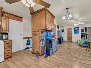 Kitchen with ceiling fan, light wood-style flooring, a textured ceiling, and brown cabinetry