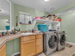 Laundry area featuring washer and dryer, light tile patterned floors, and cabinet space
