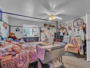 Bedroom with carpet, a textured ceiling, and a ceiling fan