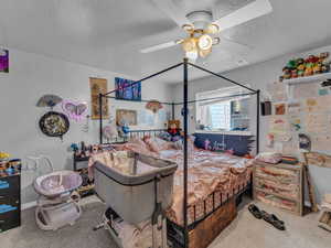 Bedroom with carpet flooring, a textured ceiling, and a ceiling fan
