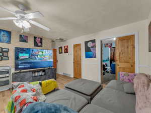 Living area with light wood-style flooring, heating unit, a textured ceiling, and ceiling fan