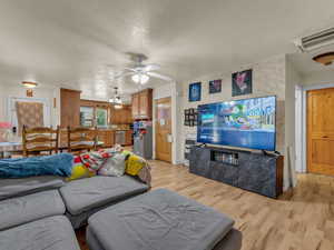 Living room with light wood-type flooring, a ceiling fan, and a textured ceiling