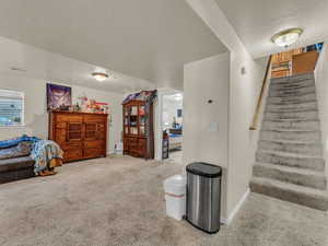 Stairway featuring a textured ceiling and carpet