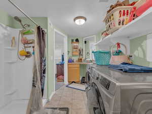 Washroom with separate washer and dryer and light tile patterned floors