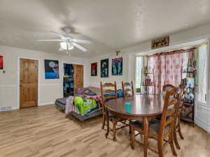 Dining area with light wood-style floors, a ceiling fan, and a textured ceiling