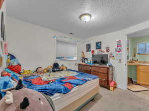 Bedroom featuring a textured ceiling and light colored carpet