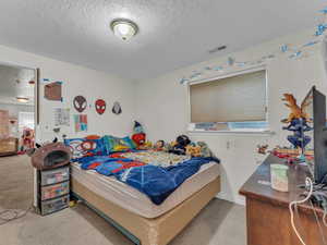 Carpeted bedroom with a textured ceiling