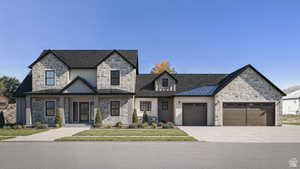 View of front of home with stone siding, concrete driveway, an attached garage, a standing seam roof, and a metal roof
