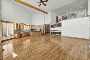 Unfurnished living room with a high ceiling, a ceiling fan, light wood-style floors, stairs, and recessed lighting