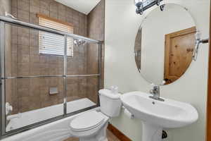Bathroom featuring combined bath / shower with glass door and toilet