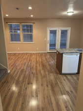 Kitchen with white dishwasher, hardwood / wood-style flooring, recessed lighting, open floor plan, and a center island