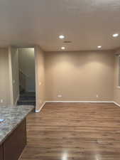 Spare room featuring wood finished floors, recessed lighting, and stairs