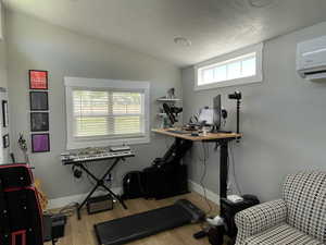 Home office with wood finished floors, lofted ceiling, and a wall mounted air conditioner