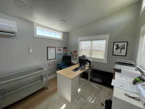 Office space featuring a wall unit AC, wood finished floors, and lofted ceiling
