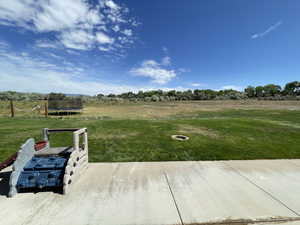 View of green lawn with a trampoline and a view of countryside back yard.