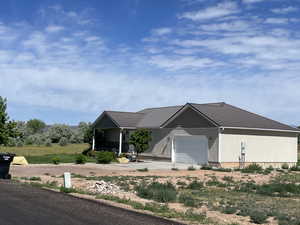 View of front of house with driveway, an attached garage, and a metal roof