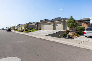 View of front facade with an attached garage, stucco siding, driveway, a residential view, and a tile roof