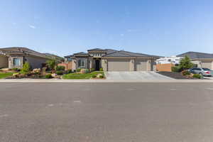 View of front of home with a garage, driveway, a tiled roof, stucco siding, and a residential view