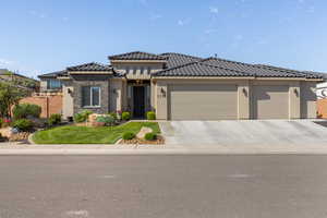 View of front of home featuring stucco siding, an attached garage, a tile roof, and driveway