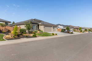 View of front of property featuring a garage, concrete driveway, stucco siding, a tile roof, and a residential view
