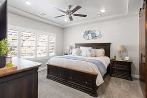 Bedroom featuring light colored carpet, a tray ceiling, ceiling fan, and recessed lighting