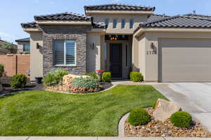 Mediterranean / spanish-style home featuring stucco siding, concrete driveway, stone siding, an attached garage, and a tiled roof