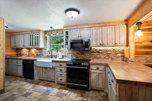 Kitchen with electric stove, black dishwasher, decorative backsplash, glass insert cabinets, and a peninsula