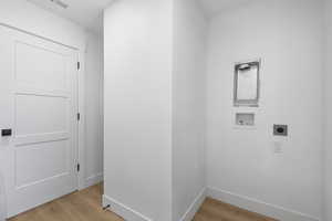 Laundry area with electric dryer hookup, hookup for a washing machine, and light wood-style floors
