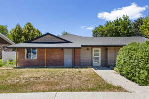 View of front of property with a front yard, brick siding, and roof with shingles