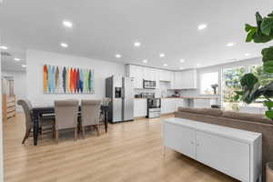 Living area with light wood finished floors and recessed lighting