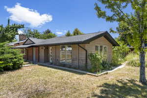 Ranch-style house with a front yard, a chimney, and roof with shingles