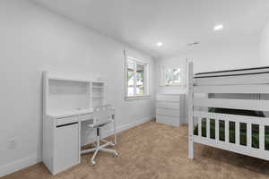 Bedroom featuring light carpet, recessed lighting, and a desk