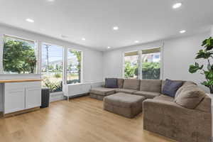 Living room with light wood finished floors and recessed lighting