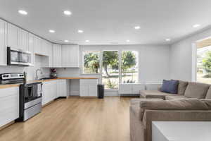 Kitchen featuring appliances with stainless steel finishes, white cabinetry, recessed lighting, light wood finished floors, and wood counters