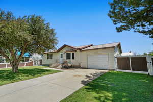Single story home with an attached garage, concrete driveway, and a metal roof