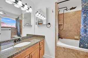 Primary bath with tiled shower and jetted tub, vanity, granite countertops, newer bathroom hardware in tub/shower and sink