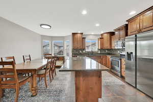 Kitchen featuring stainless steel appliances, decorative backsplash, a center island, dark stone counters, and recessed lighting