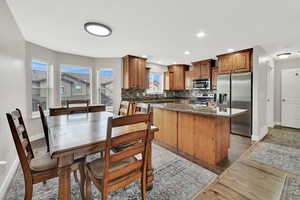Kitchen with stainless steel appliances, a kitchen island, tasteful backsplash, recessed lighting, and dark stone counters