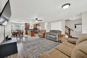 Great room with wood finished floors, stairway to second level, and ceiling fan