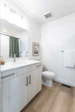 Full bath with vanity, wood finished floors, and a shower with curtain