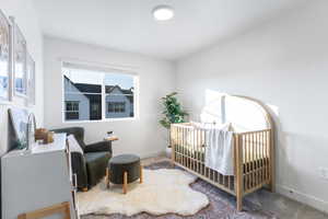 Carpeted bedroom featuring baseboards and a crib