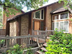 View of front of home featuring brick siding and a deck.