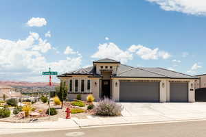Prairie-style house with a garage, concrete driveway, stucco siding, a tile roof, and a mountain view
