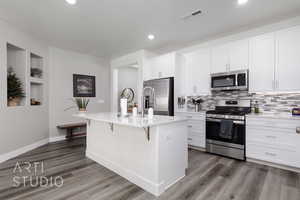 Kitchen featuring stainless steel appliances, recessed lighting, a breakfast bar area, backsplash, and dark wood-style floors
