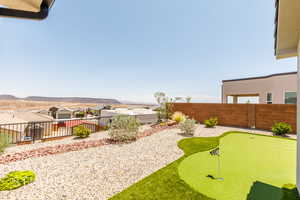 Fenced backyard featuring a putting green