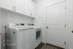 Laundry room with washing machine and clothes dryer, cabinet space, and dark wood-style flooring